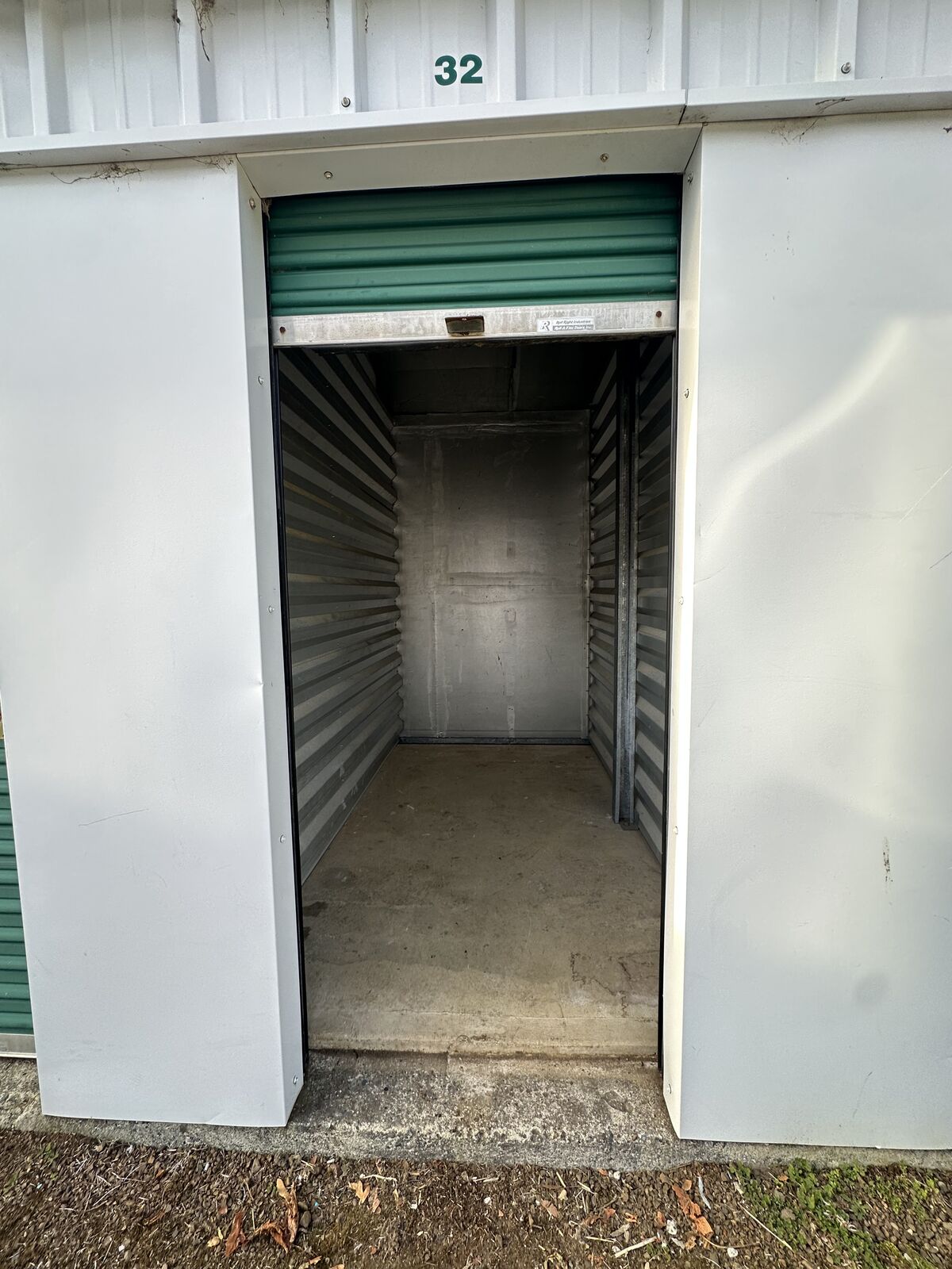 Empty storage unit with its green roll-up door raised